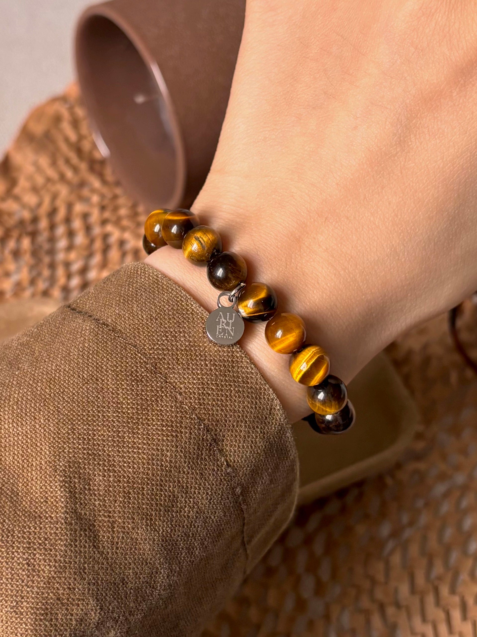 Aurien Crystal golden Tiger’s Eye 6mm bracelet styled with warm brown jacket, autumn outfit ideas in natural color palette, minimalist gemstone jewelry for courage and grounding.
