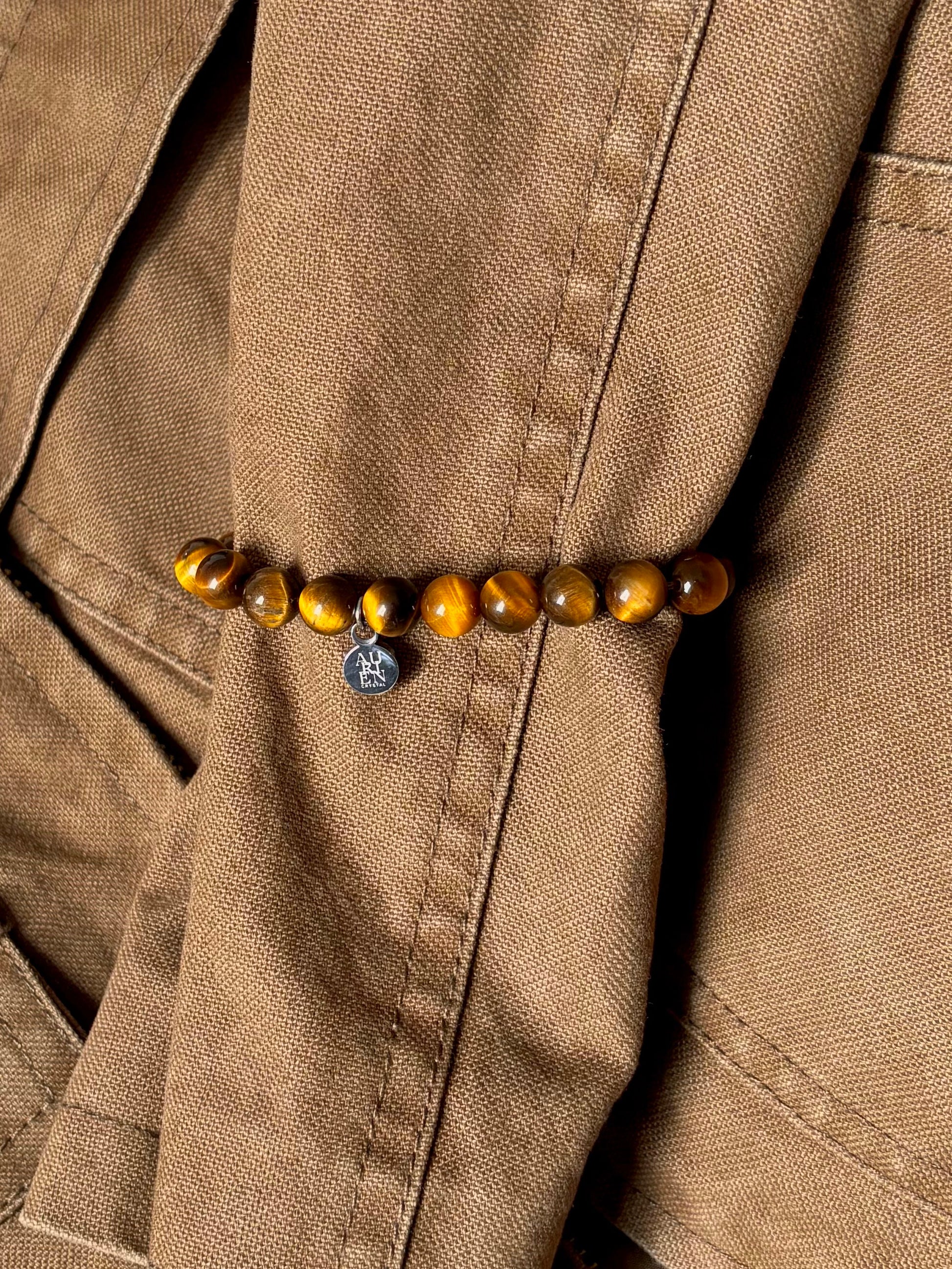 Golden Tiger’s Eye 6mm bracelet styled with warm brown jacket, autumn outfit ideas in natural color palette, minimalist gemstone jewelry for courage and grounding.